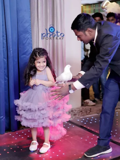 The birthday girl's older sister is delighted by a magician's dove at the party. I focus on capturing the experiences of all family members, not just the child of honor.