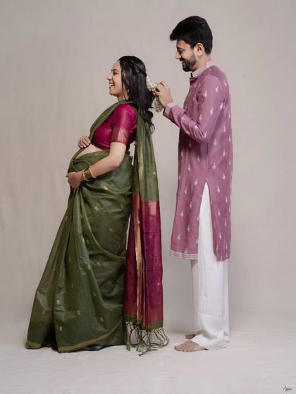 This is a quiet moment of care. As he gently places flowers in her hair, we see a story of partnership and tradition. We chose a simple, neutral backdrop to let their traditional attire and their connection be the focus of this Indian maternity portrait.