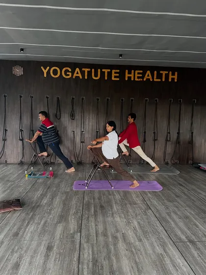 Using a chair to support a lunge variation. This modification helps students work on hip flexibility and leg strength without putting excessive pressure on the joints, making the pose accessible to everyone.