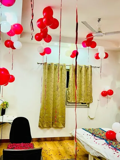 This image shows how I decorate the entire room, not just the bed. Balloons hanging from the ceiling and a chair decorated with rose petals make the whole space feel special.