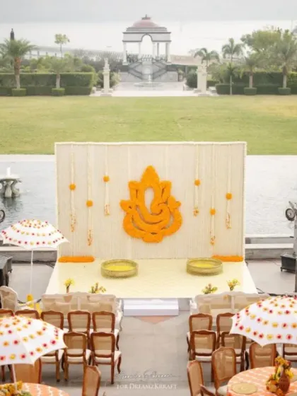 A traditional Haldi setup at Raffles Udaipur, with a backdrop featuring a Ganesha made of marigolds. The seating with custom-printed umbrellas adds a touch of local artistry.