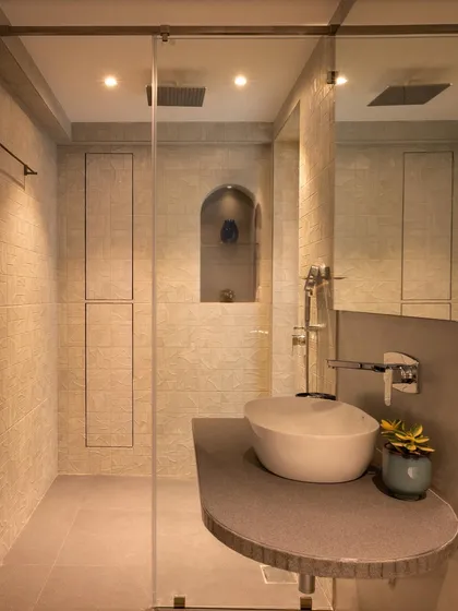 This angle of the master bathroom highlights the curved vanity counter and vessel sink. The warm, ambient lighting and seamless storage panels contribute to a serene and spa-like atmosphere.