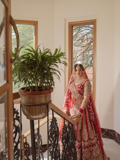 A beautiful bridal portrait on a staircase. The bride's traditional red lehenga and her elegant pose create a classic and timeless image.