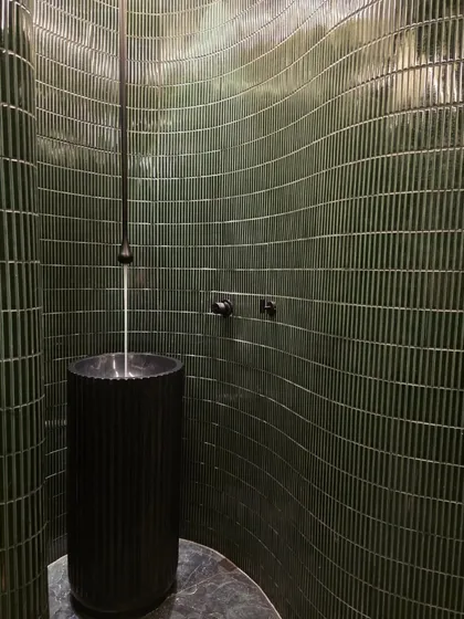 I'm not afraid of a little drama, and this powder bathroom is proof. The curved wall with deep green, textured tiles and a sleek pedestal sink creates a moody, unforgettable statement.
