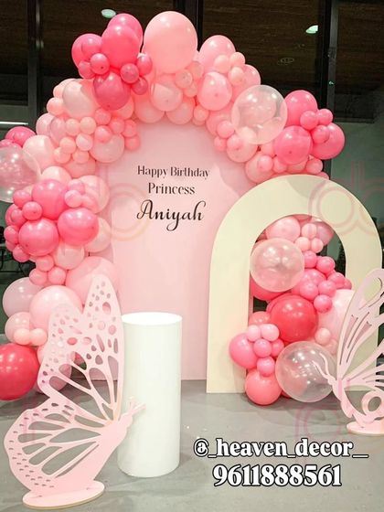 A modern and chic butterfly theme using shades of pink for a "Princess" birthday. The setup features two arched backdrops, a dense balloon garland, and minimalist laser-cut butterfly props.