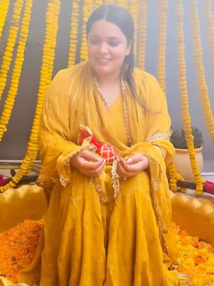 A happy bride-to-be during her Haldi ceremony, seated in one of our custom-decorated urlis filled with marigold petals.