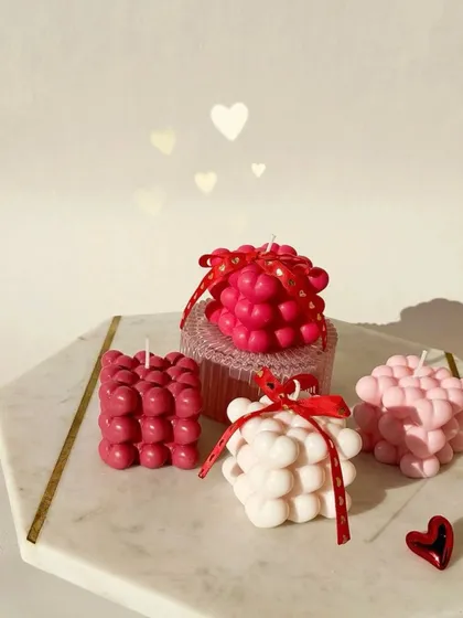 Heart-shaped bubble candles in various shades of pink and red, some tied with ribbons for gifting.