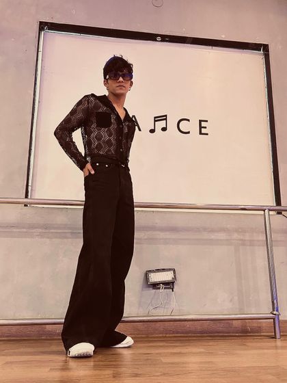 A full-length shot in the dance studio, showing my retro-inspired outfit with flared pants and a sheer shirt.