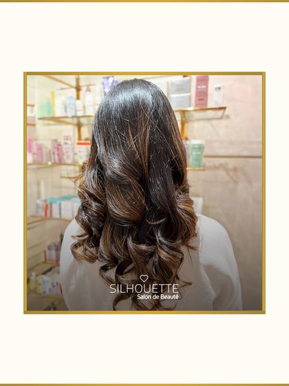 Elevate your look with sophisticated tones that add elegance. Here, carefully placed highlights within soft curls create a dimensional and polished finish.