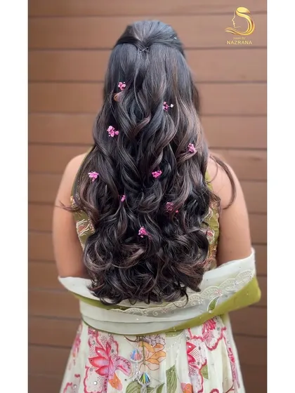 A half-up style with soft curls, adorned with delicate pink baby's breath.
