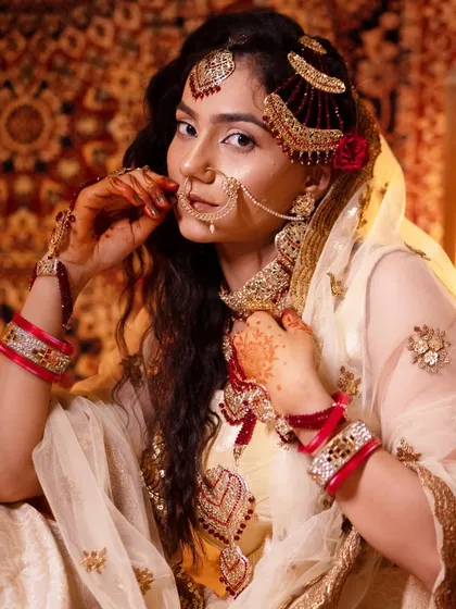 This image captures the classic bridal pose, highlighting the intricate nose ring and hand jewelry that are part of the complete look.