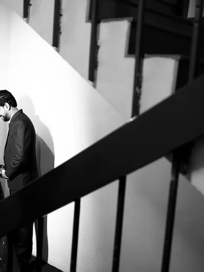 A dramatic black and white shot of a couple on a staircase. The strong lines and contrast create a powerful, artistic image that symbolizes their journey together.