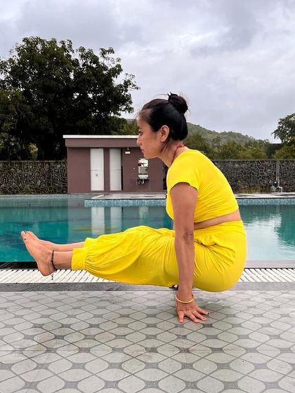 Brahmacharyasana, or celibacy pose, by the poolside. This L-sit hold is a powerful test of core and arm strength.