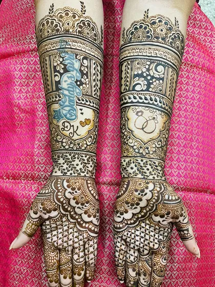 An engagement mehendi with a special touch. The bride's name, 'Divya', is written in a beautiful script on one arm, with the couple's initials 'DK' below it.