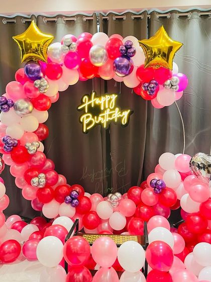 A vibrant pink, red, and silver balloon ring with a neon sign, perfect for a lively celebration.