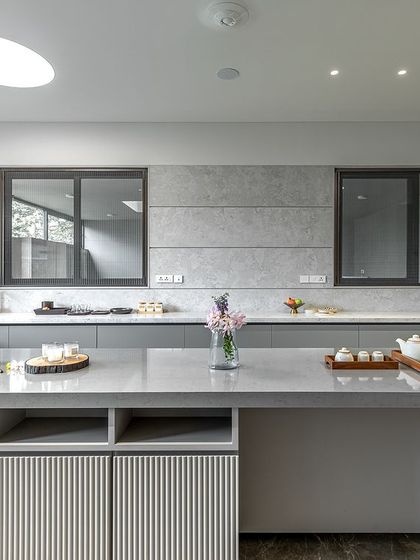 The island in Niketa Lalit Patel's kitchen features open shelving and a unique ribbed texture on the drawer fronts, adding a subtle decorative detail to the minimalist design.