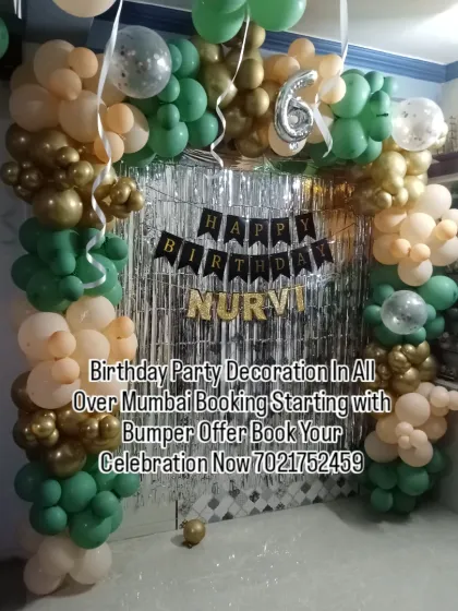 A stylish home decoration with a green, peach, and gold balloon arch. The silver shimmer curtain and personalized name banner make this a great setup for a 6th birthday.