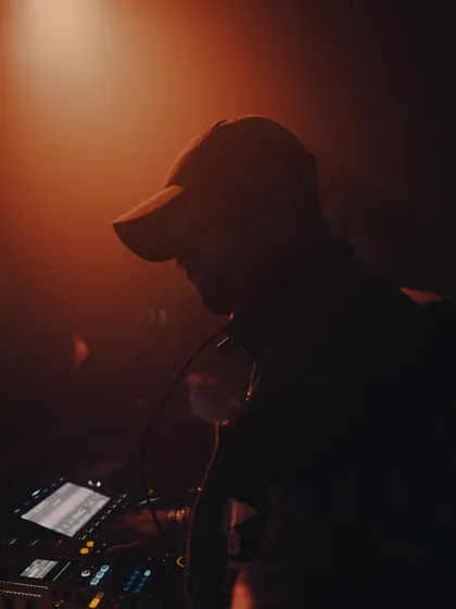 A silhouette shot of me at the decks, bathed in a warm, hazy orange light. This captures the focused, intense mood of a late-night techno set.