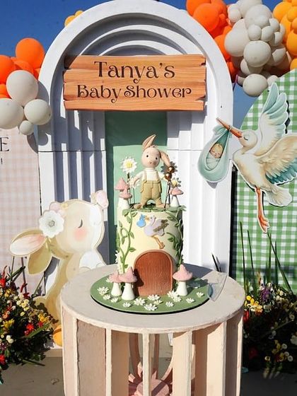 A detailed view of the bunny-themed cake table. The custom cake, shaped like a bunny's burrow, sits perfectly within the larger garden-themed backdrop.