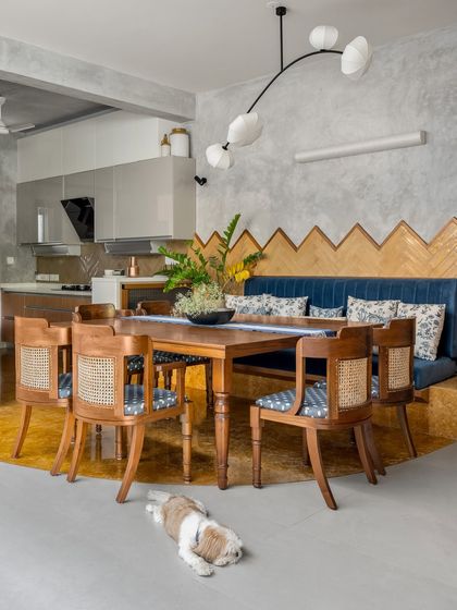 A dining space designed for family life, complete with a furry friend. The custom bench seating and cane chairs are paired with a modern chandelier, creating a stylish yet informal setting.