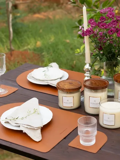 Create your own bespoke collection by mixing candle heights and votive shapes. Here, our glass jar candles with rosewood lids are paired with taper candles to amplify the atmosphere for a special dinner.