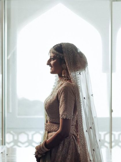 A silhouette of the bride against a bright window, her profile elegant and timeless. This artistic portrait uses light and shadow to create a sense of quiet contemplation.