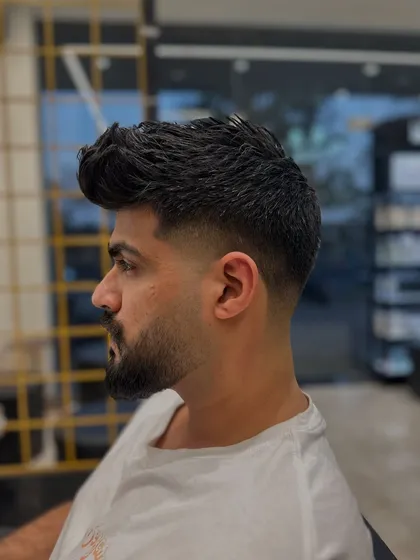 This is a great example of how a fade and beard can work together. The hair fades down to the skin and then blends back into the full, well-defined beard for a strong, masculine style.