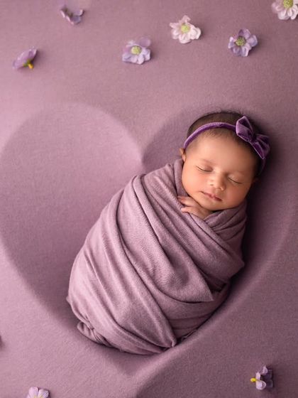 This little sweetheart is wrapped snugly inside a heart-shaped outline. The soft purple tones and scattered flowers make this a truly romantic and lovely portrait.