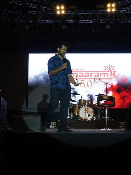 A full-stage view of Naveen Richard's comedy show, highlighting the event branding and setup.