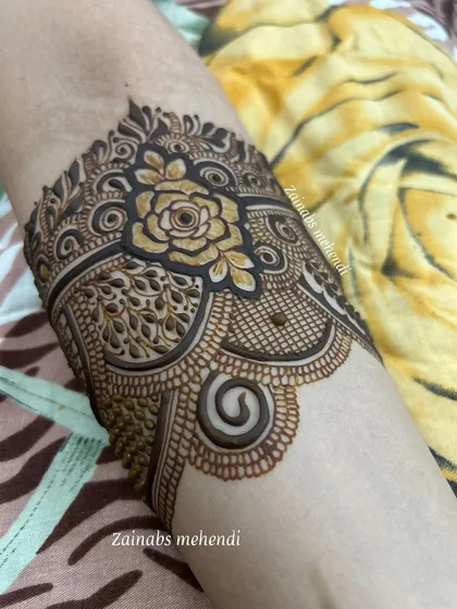 A close-up of the armband on Ameena's engagement henna, highlighting the central rose motif.