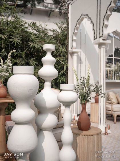 A grouping of modern, sculptural white vases of various shapes and sizes, used as a key decorative element in the ivory-themed wedding.