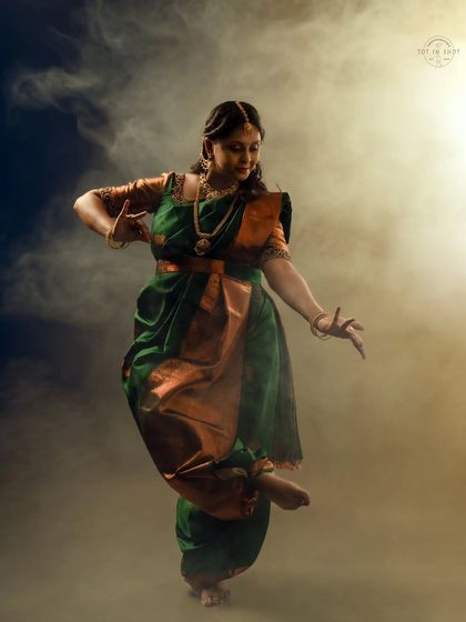 A dramatic dance pose captured with atmospheric smoke, highlighting the movement of the saree and the grace of the mother-to-be.