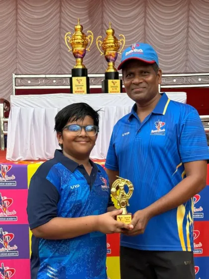 A player receives his award from a coach at the U-10 presentation ceremony, with the winner's trophies displayed in the background.