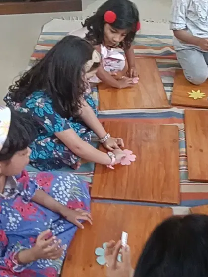 A close-up of little hands carefully placing paper flowers, showing the development of fine motor skills.