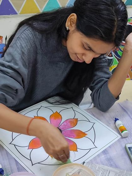 A student carefully adding colored powder to her rangoli. The process is as beautiful and meditative as the final result.
