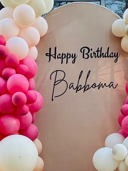 A close-up of a personalized arched backdrop, showing the custom name and a vibrant pink balloon arrangement.