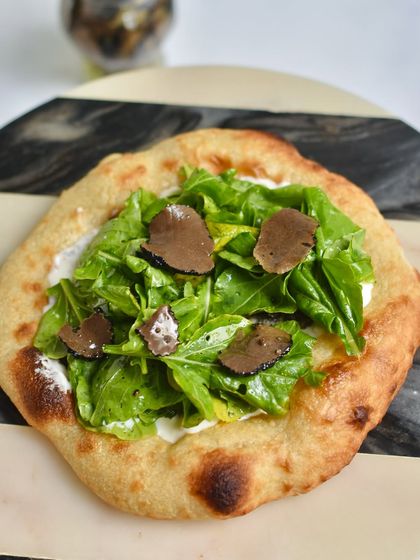 Our Truffle Sourdough Flatbread was a huge hit at our Spanish popup. It's topped with creamy cheese, fresh arugula, and shaved black truffle for an earthy, decadent flavour.