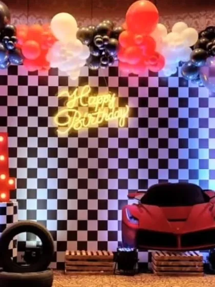 A stylish race car theme with a black-and-white checkered backdrop, a red Ferrari prop, and a neon "Happy Birthday" sign.