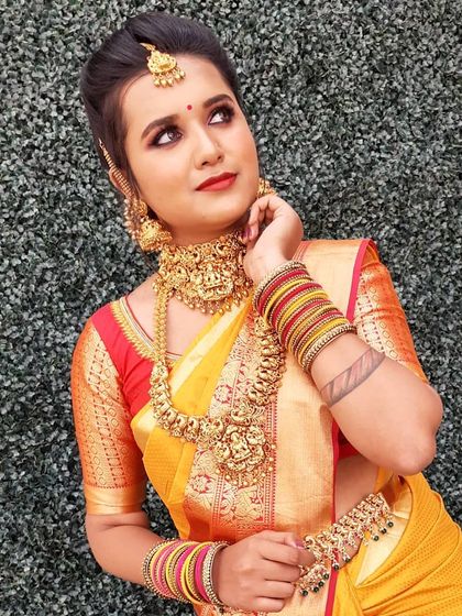 This look captures a radiant festive glow. The makeup is bright and fresh, with attention to highlighting the skin and complementing the client's features and colorful saree.