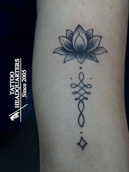 A beautiful Unalome tattoo paired with a shaded lotus flower, symbolizing the path to enlightenment and purity.
