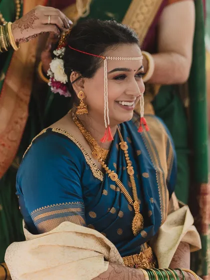 A candid moment during the wedding rituals. The traditional 'mundavalya' looks beautiful against her soft, subtle makeup, designed to last through all the ceremonies.
