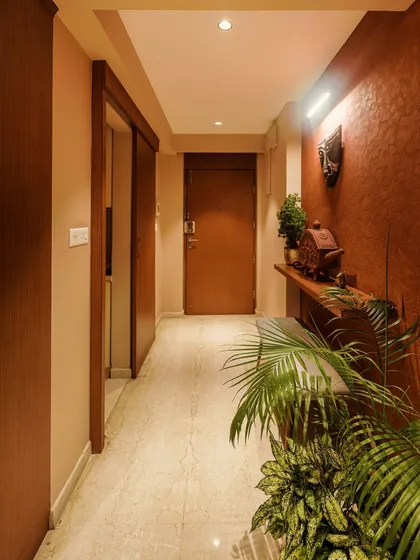 A view of the hallway from image 4, showing the terracotta wall and lush indoor plants.