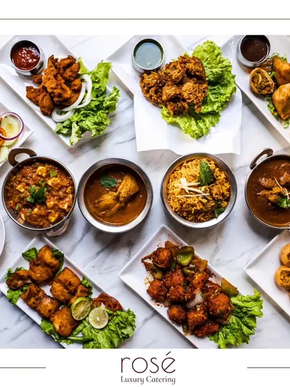 A stunning top-down view of a complete Indian feast, featuring a variety of curries, kebabs, biryani, and appetizers. We bring top-tier, diverse culinary delights to your most cherished moments.