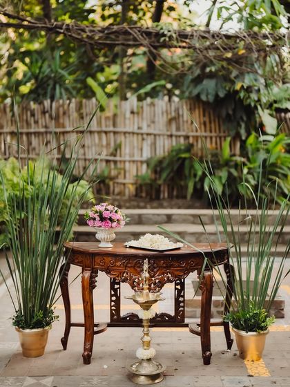 An antique wooden table set with a brass lamp and flowers, creating a charming welcome corner.
