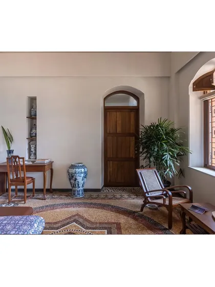 This restored living space showcases the harmony between different elements. The rich tones of the salvaged wood furniture and doors stand out against the intricate patterns of the china mosaic floor.