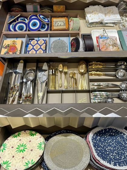 A unique drawer with custom zig-zag detailing, organized with fine cutlery, placemats, and decorative items. This shows our ability to work with any style of cabinetry.