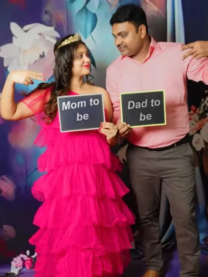 A fun shot for a growing family. The expecting parents and their son hold up 'Mom to be' and 'Dad to be' signs.