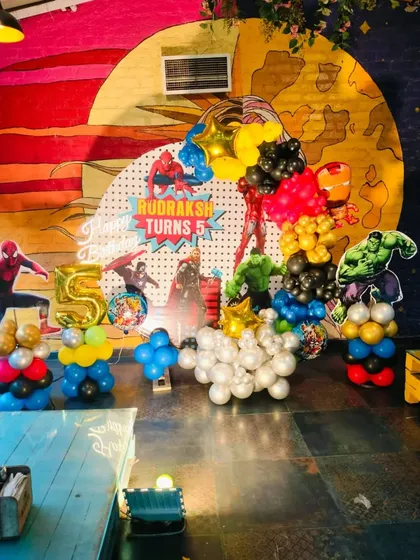 A powerful superhero-themed party featuring the Avengers. This setup includes character foil balloons of Iron Man and Hulk, a custom backdrop, and a large foil number '5'.