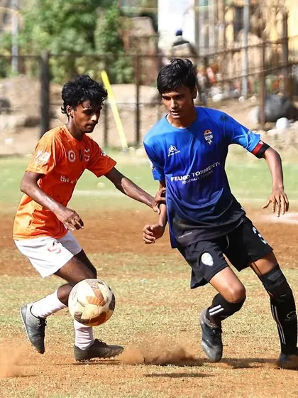 Dust kicks up as two players challenge for the ball, showing the intensity of the game.