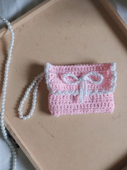 A still photo of the lovely pink and white crochet bow wallet.